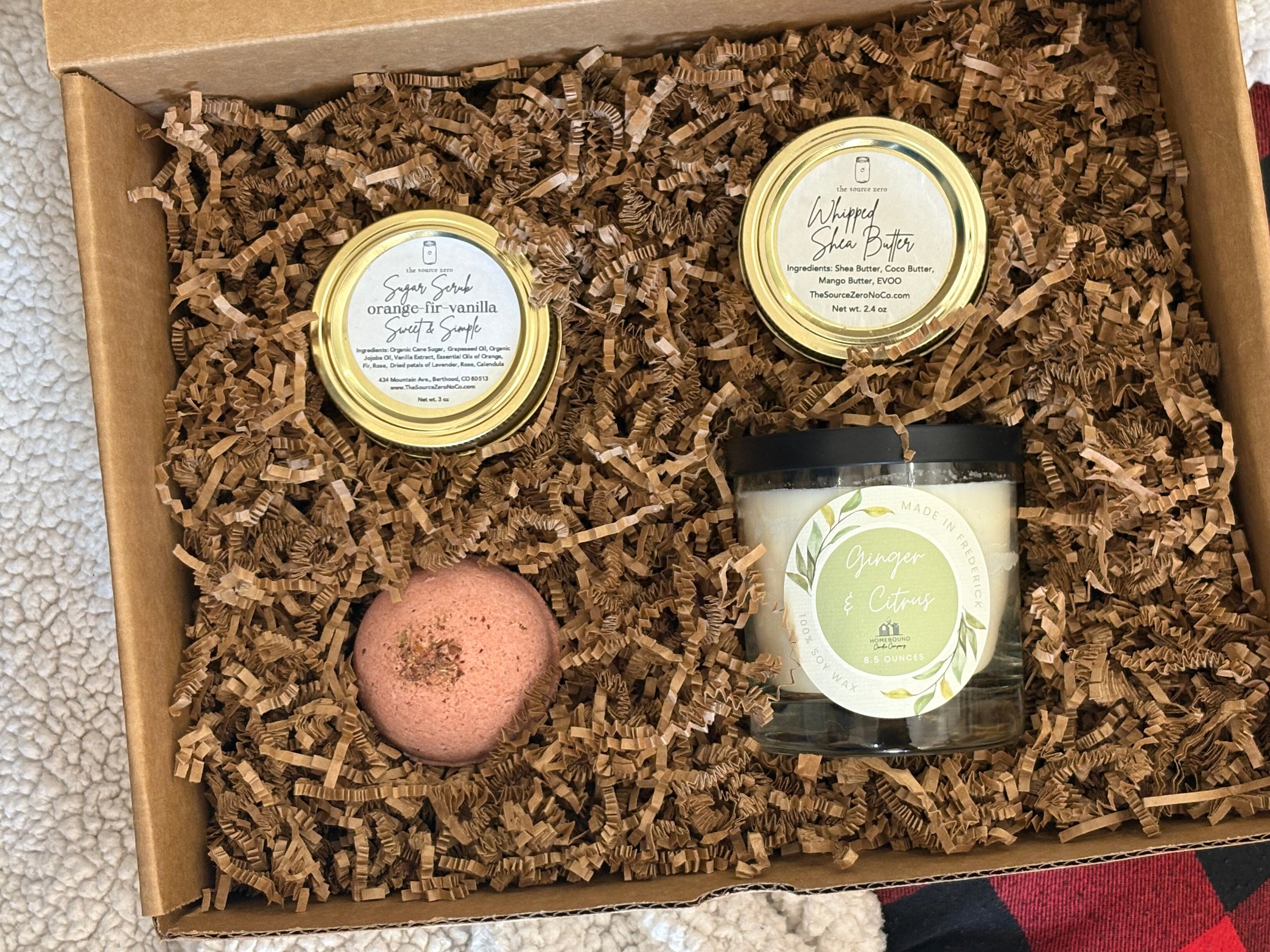 Gift set of bath products including whipped shea butter, sugar scrub, bath bomb, and hand poured candle. 